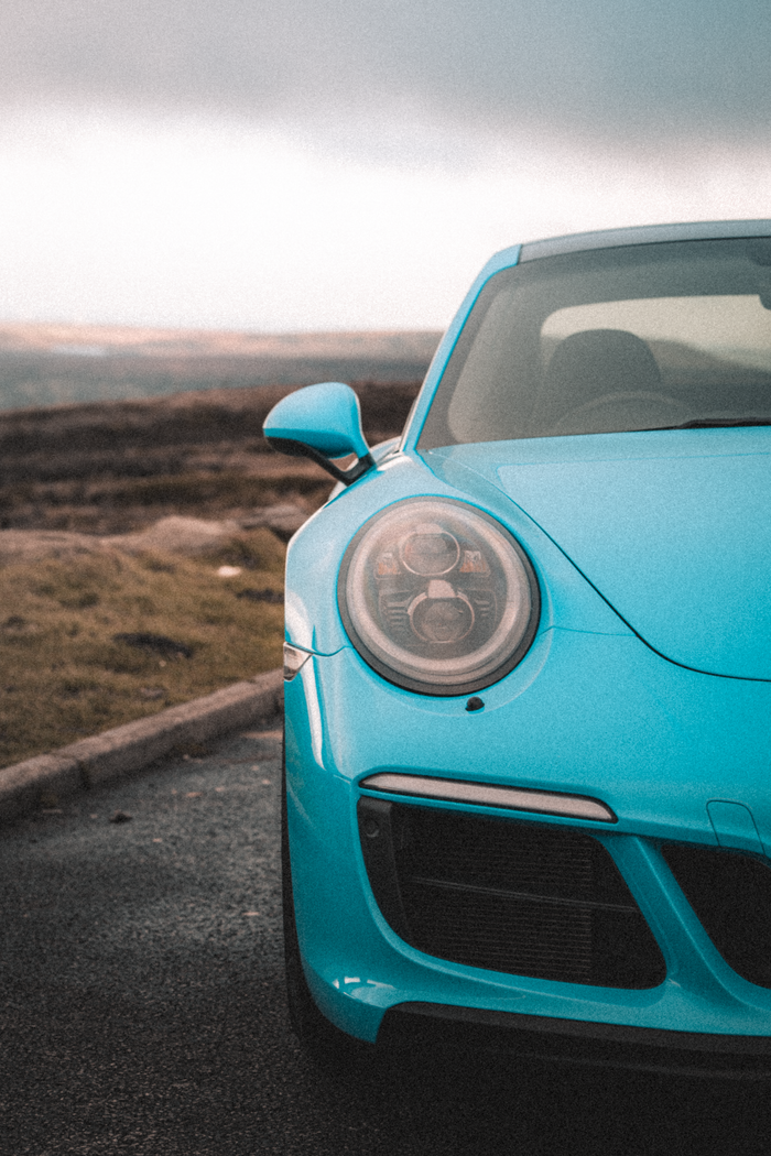 services-01 Dynamic shot capturing a blue sports car on an open road with Manchester's countryside backdrop.