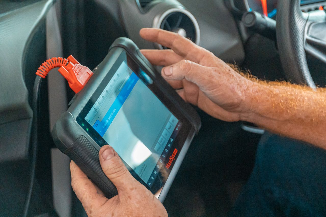 why-choose-us A mechanic uses a diagnostic tablet inside a car for vehicle analysis.