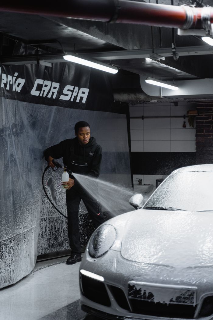 hero-img-02 Efficient car wash by a skilled worker at a modern garage, ensuring a spotless vehicle.